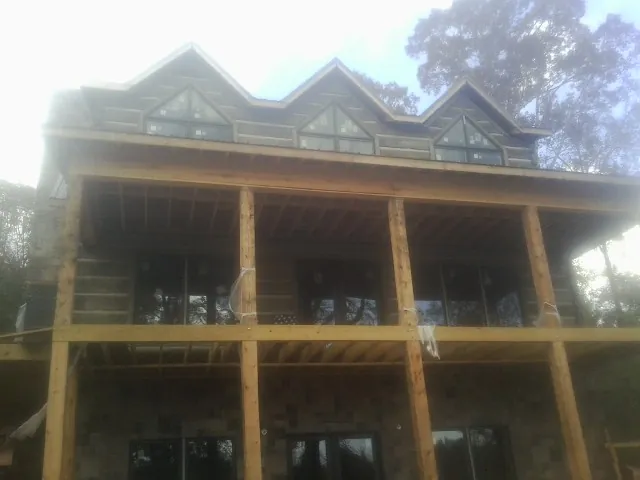 Dormers and porch framing on a large log home under construction — Roof Coating work by our crew in Zionville