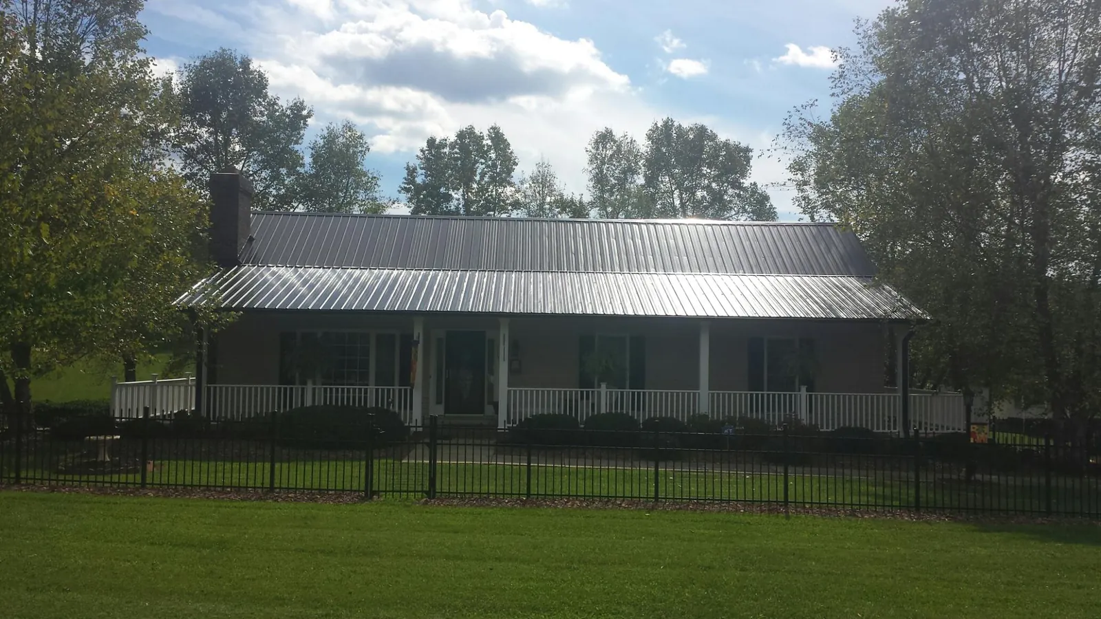 Gray metal roof on a brick ranch with a full width front porch — Gutter Guard Installation work by our crew in Zionville