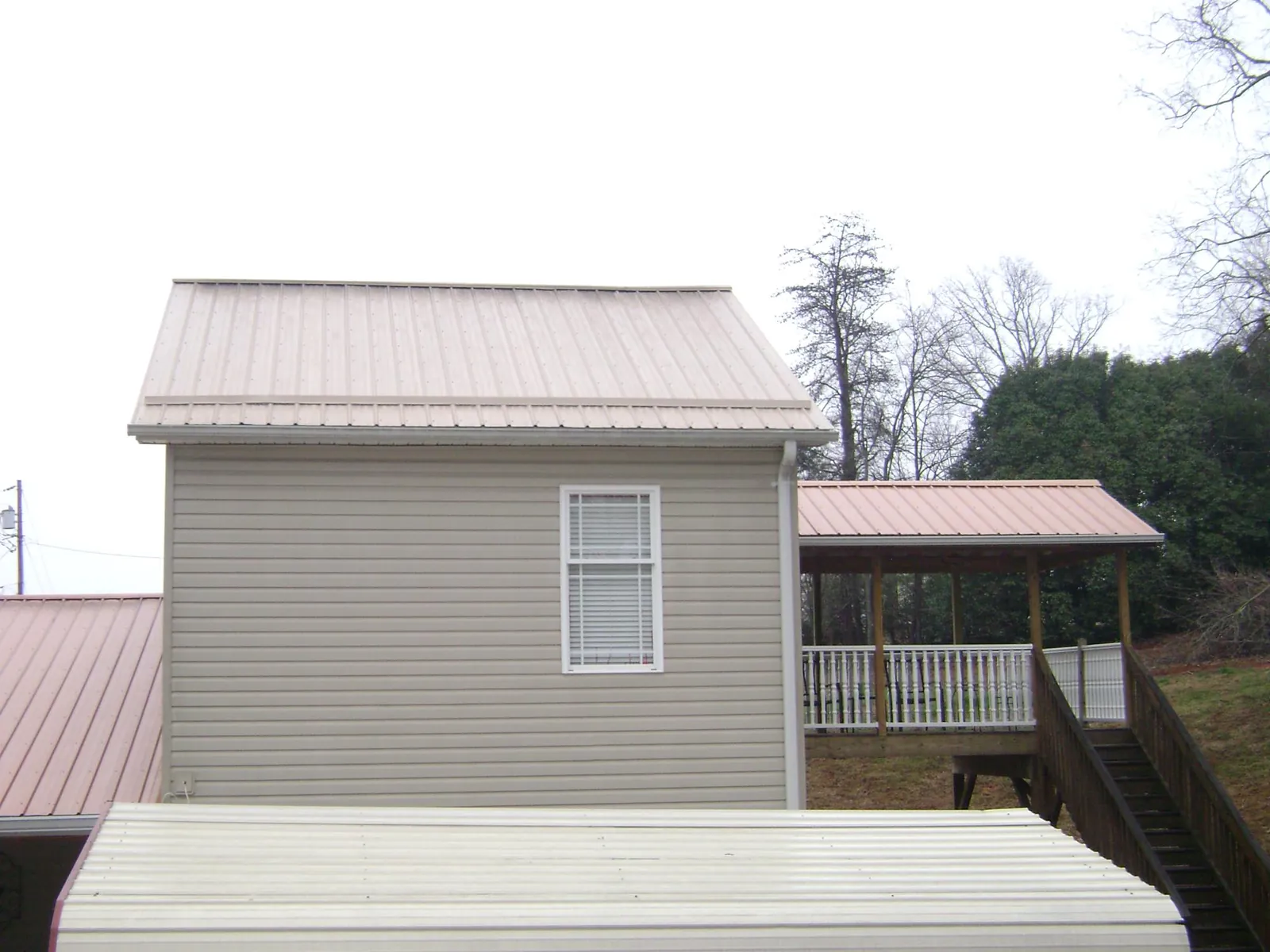 Tan metal roofs on a two story addition and attached porch, from a Roof Replacement job in Zionville