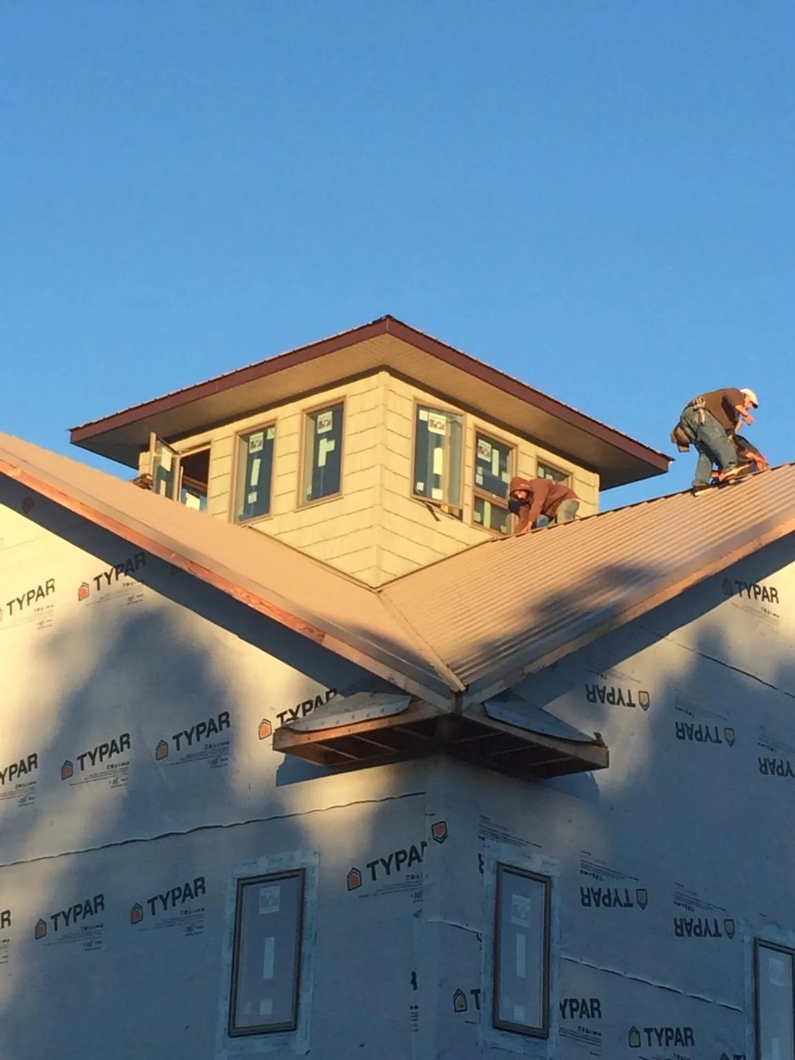 Roofers working around a rooftop cupola on a new metal roof at sunset — Roof Waterproofing in Zionville by Roofing Brothers